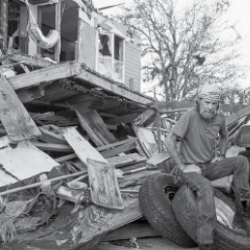 A resident of storm-racked Lake Charles, Louisiana, sits in from of his damaged house.