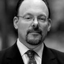 Headshot of man with glasses and suit and tie