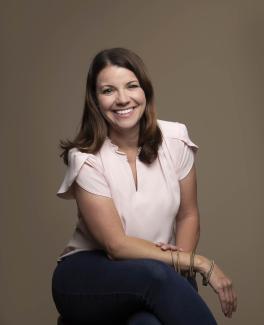 Simone smiling as she sits on a chair.